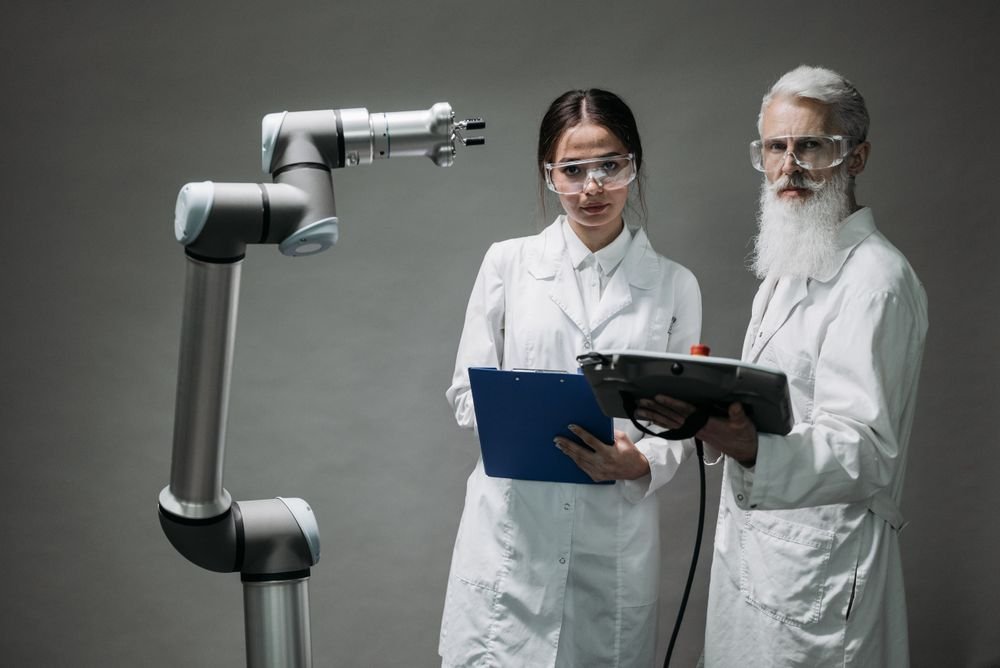 Engineers programming a collaborative robot arm with a tablet in a technology lab